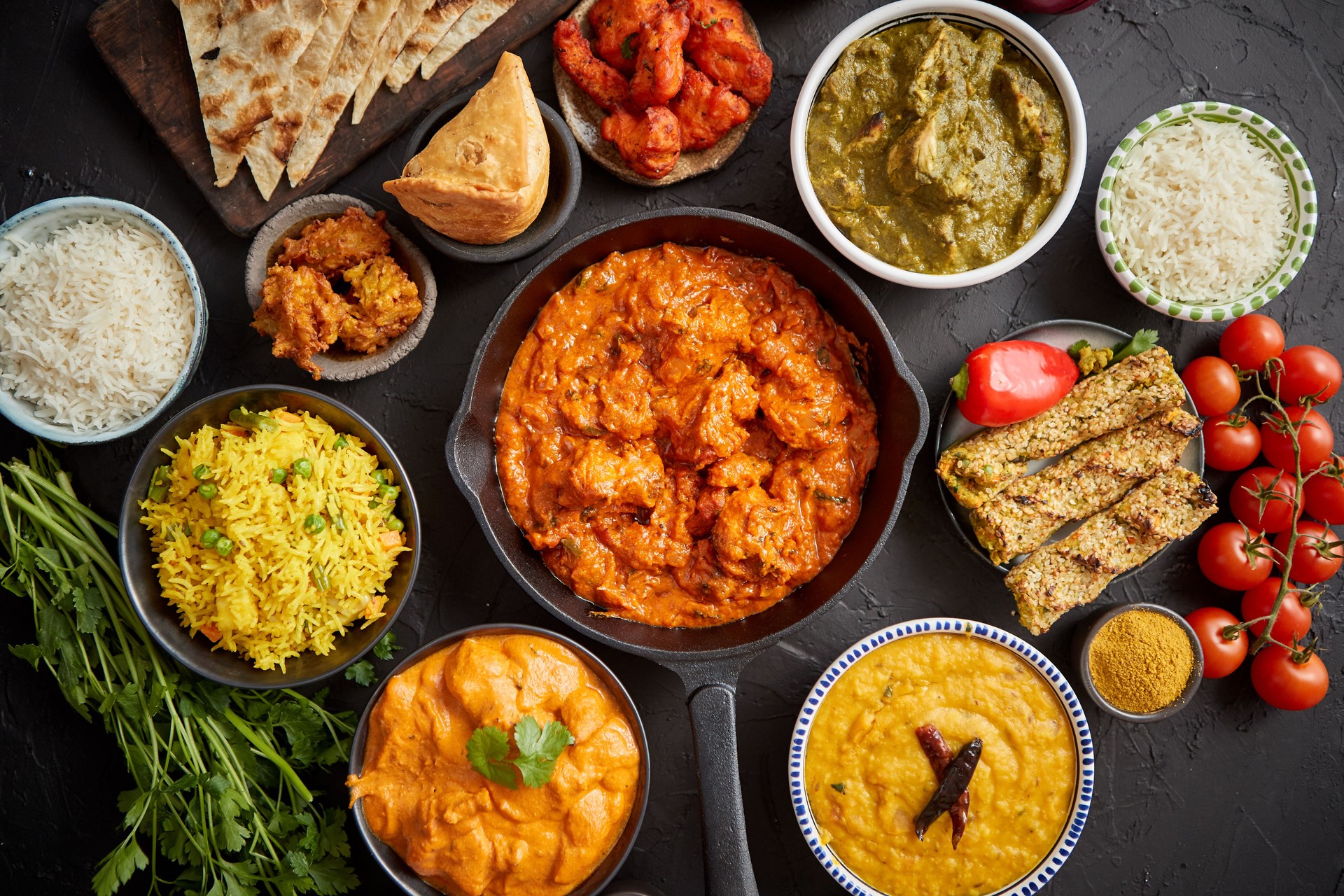 Assortment of various kinds of Indian cousine on dark rusty table